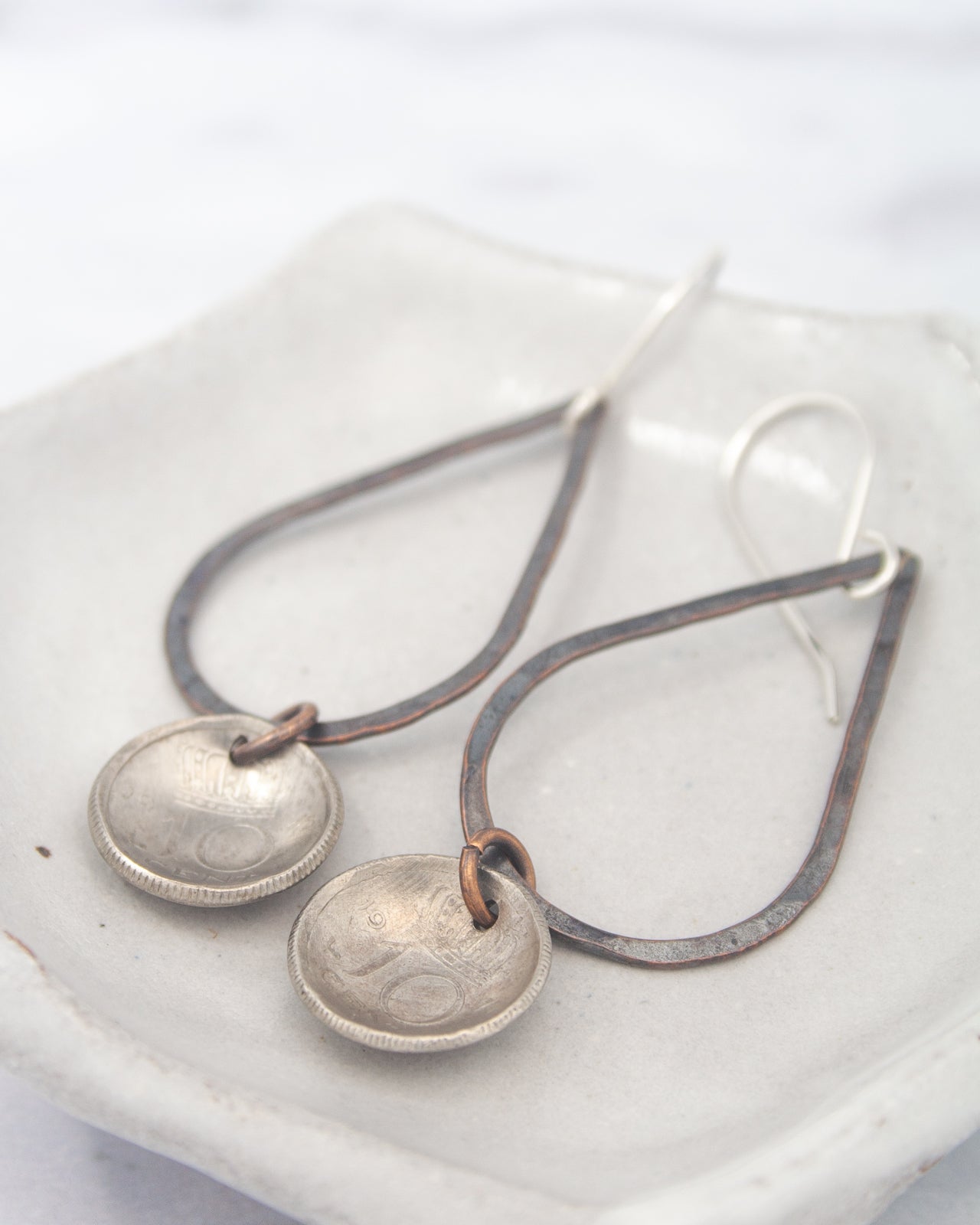 A pair of silver earrings with metal pendants hanging from a metal frame.