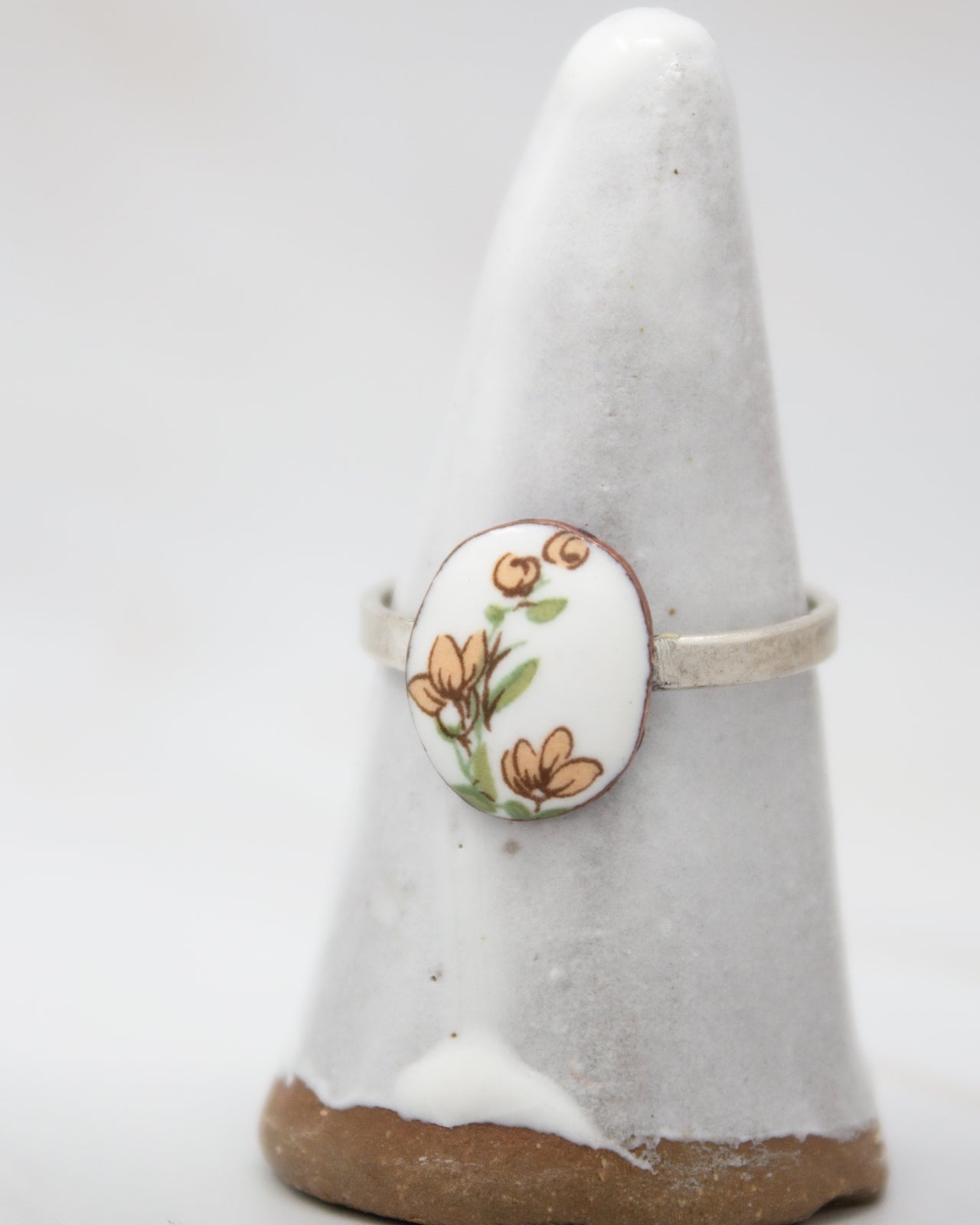 A white ceramic ring stand with a floral design on it.