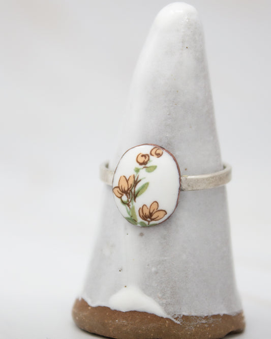 A white ceramic ring stand with a floral design on it.