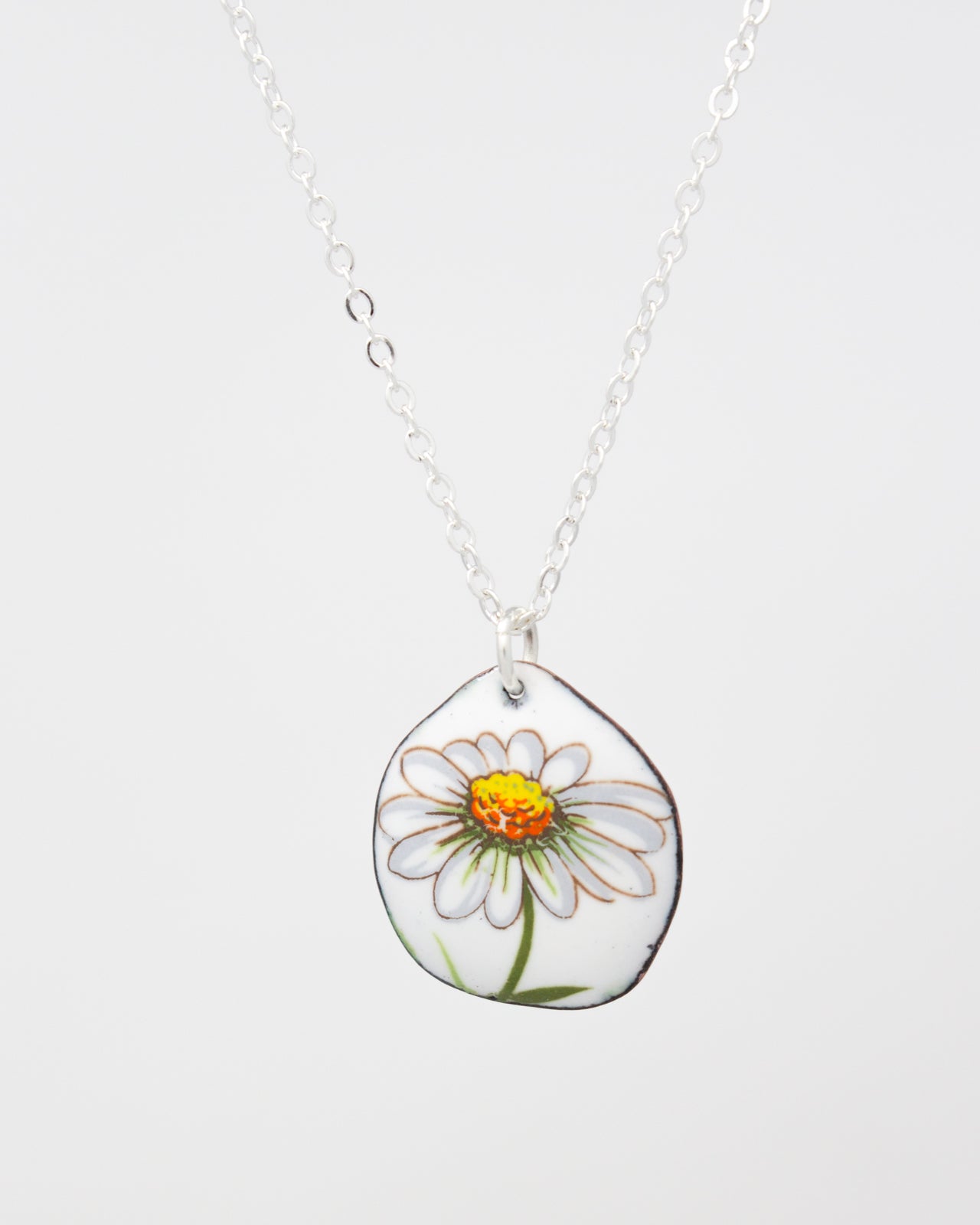 A necklace with a pendant featuring a white daisy flower with a yellow center.