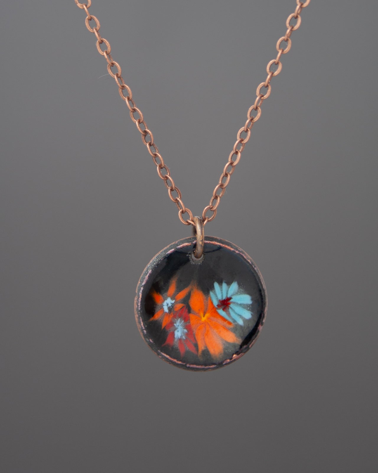 A necklace with a circular pendant featuring a floral design in various colors.