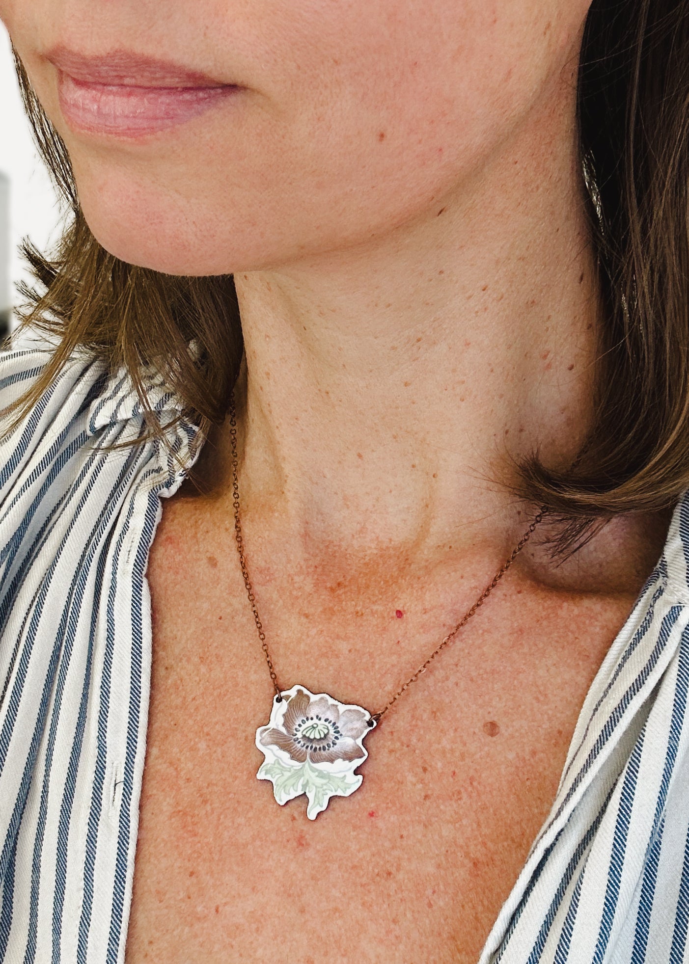 a woman wearing a necklace with a rose on it