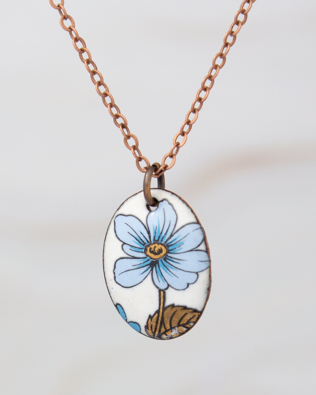 A necklace with a pendant featuring a blue flower design.