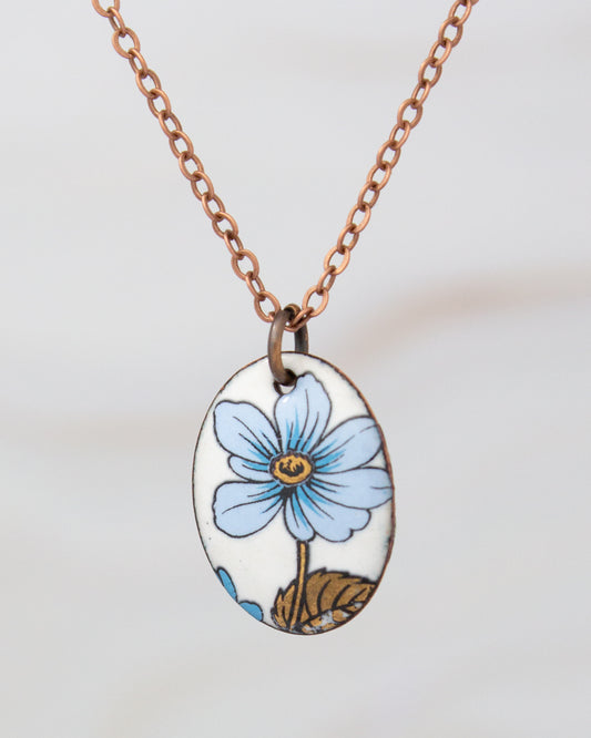 A necklace with a pendant featuring a blue flower design.