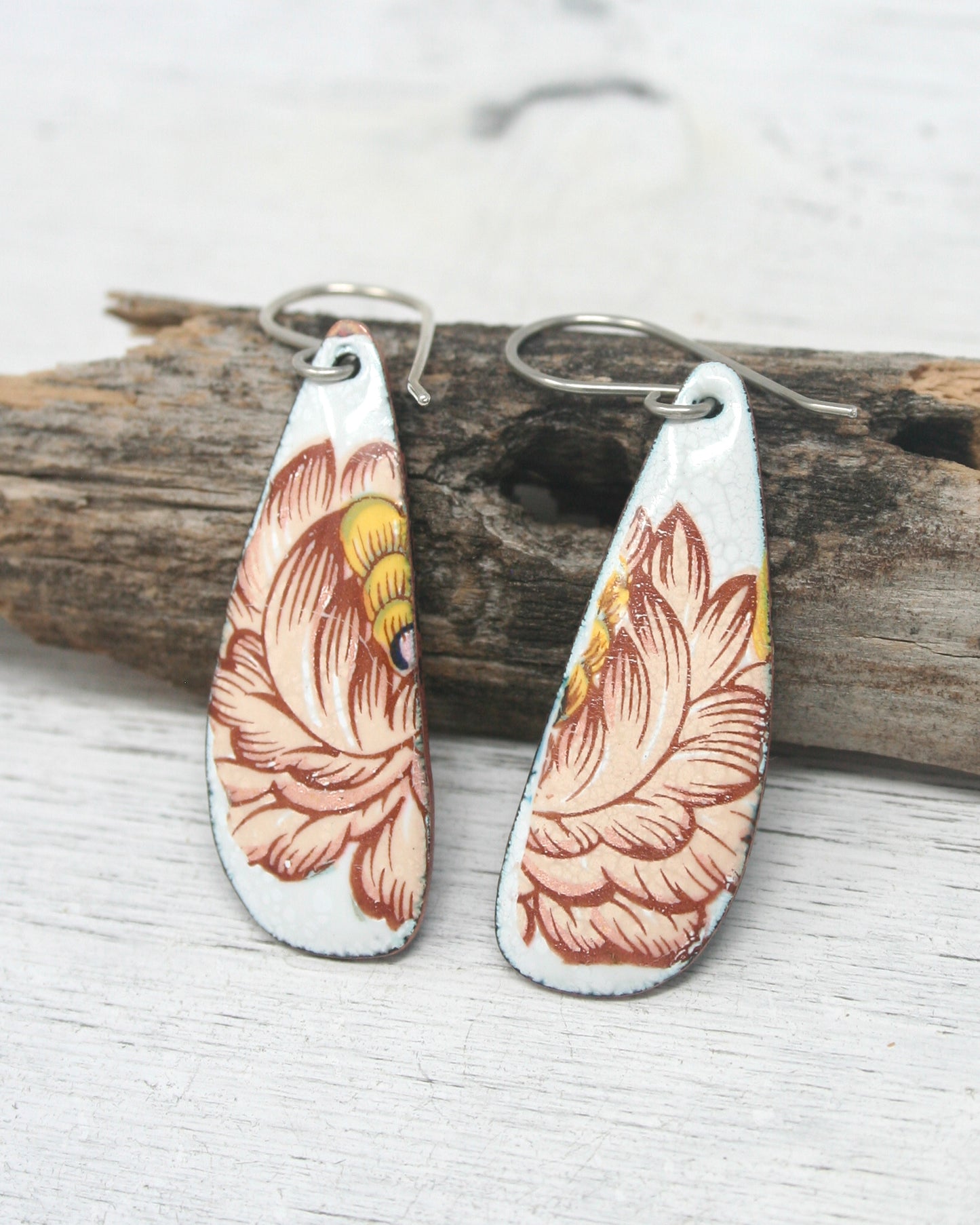 a pair of earrings sitting on top of a piece of wood