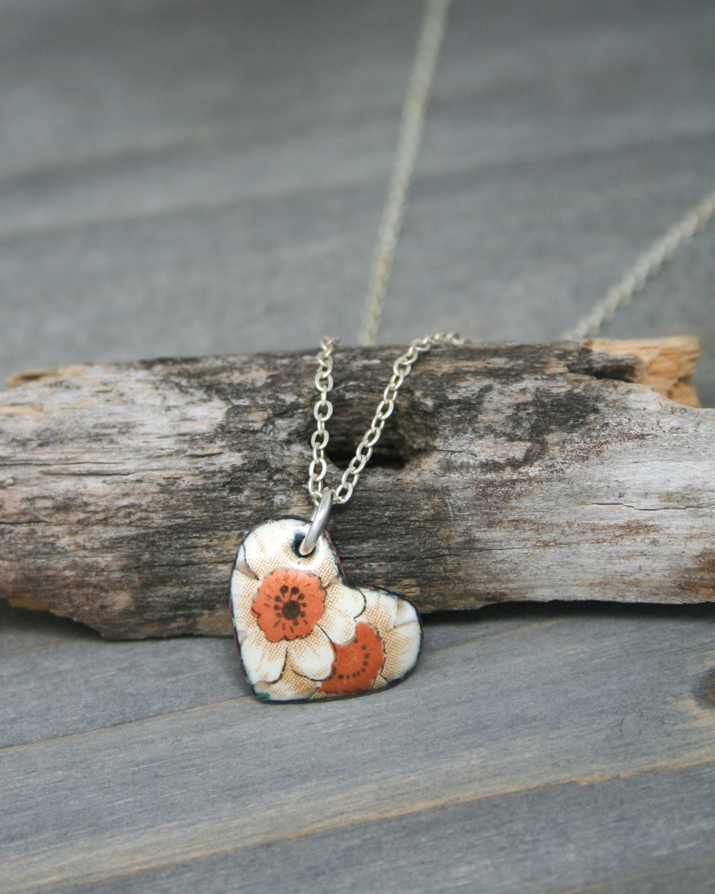 a necklace with a flower on it sitting on a piece of wood