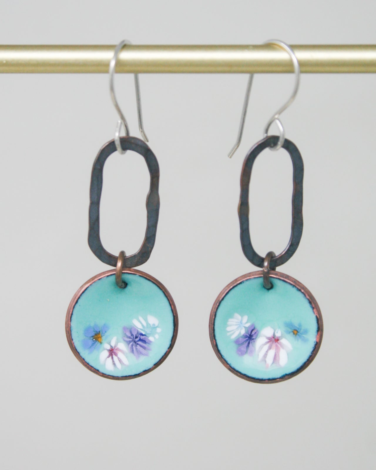 a pair of earrings with flowers painted on them