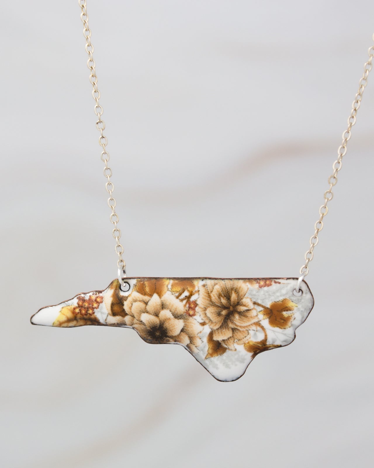 A necklace with a pendant in the shape of the state of North Carolina.
