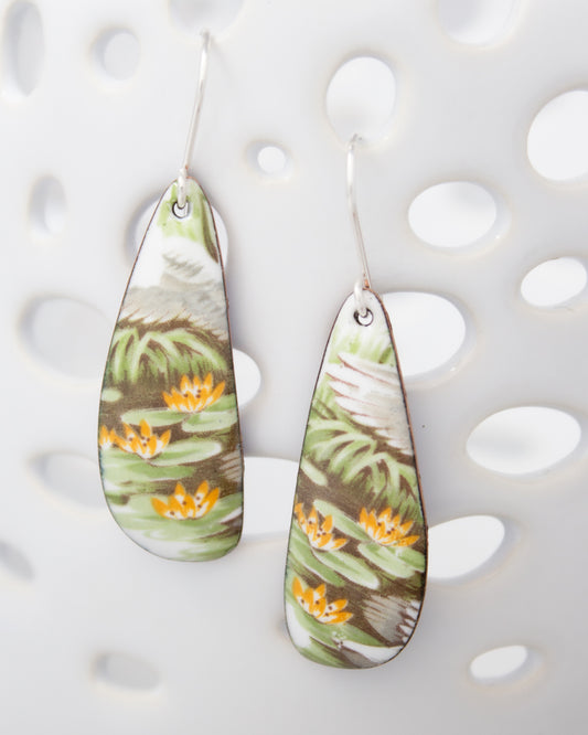 A pair of earrings with a floral pattern, featuring green and orange elements, hanging against a white background.