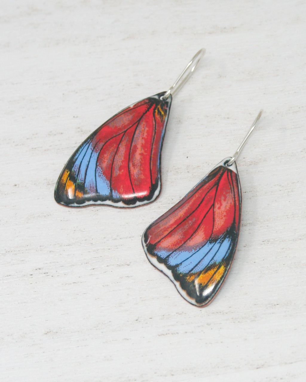 a pair of butterfly shaped earrings on a white surface