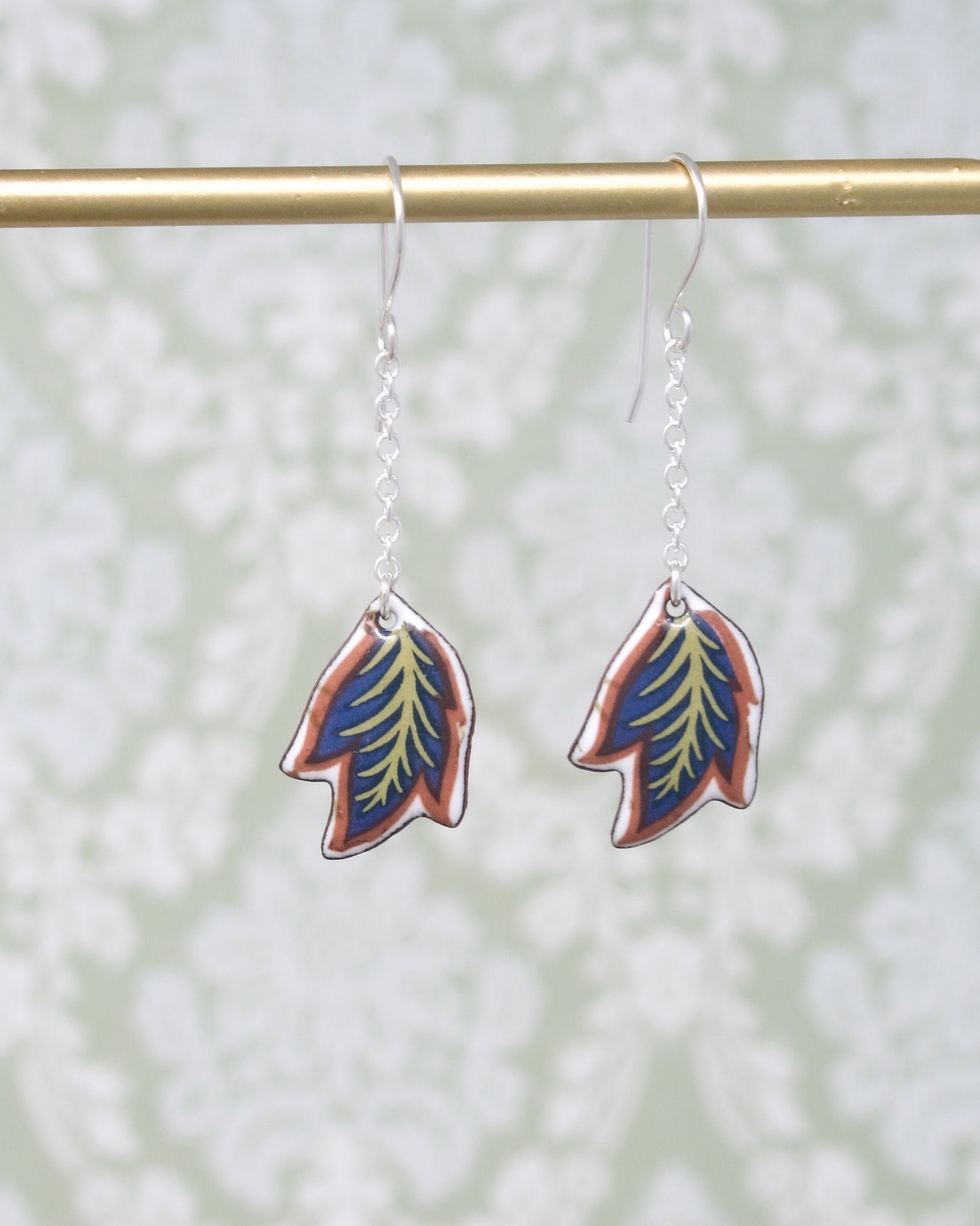 a pair of earrings with a leaf design on them