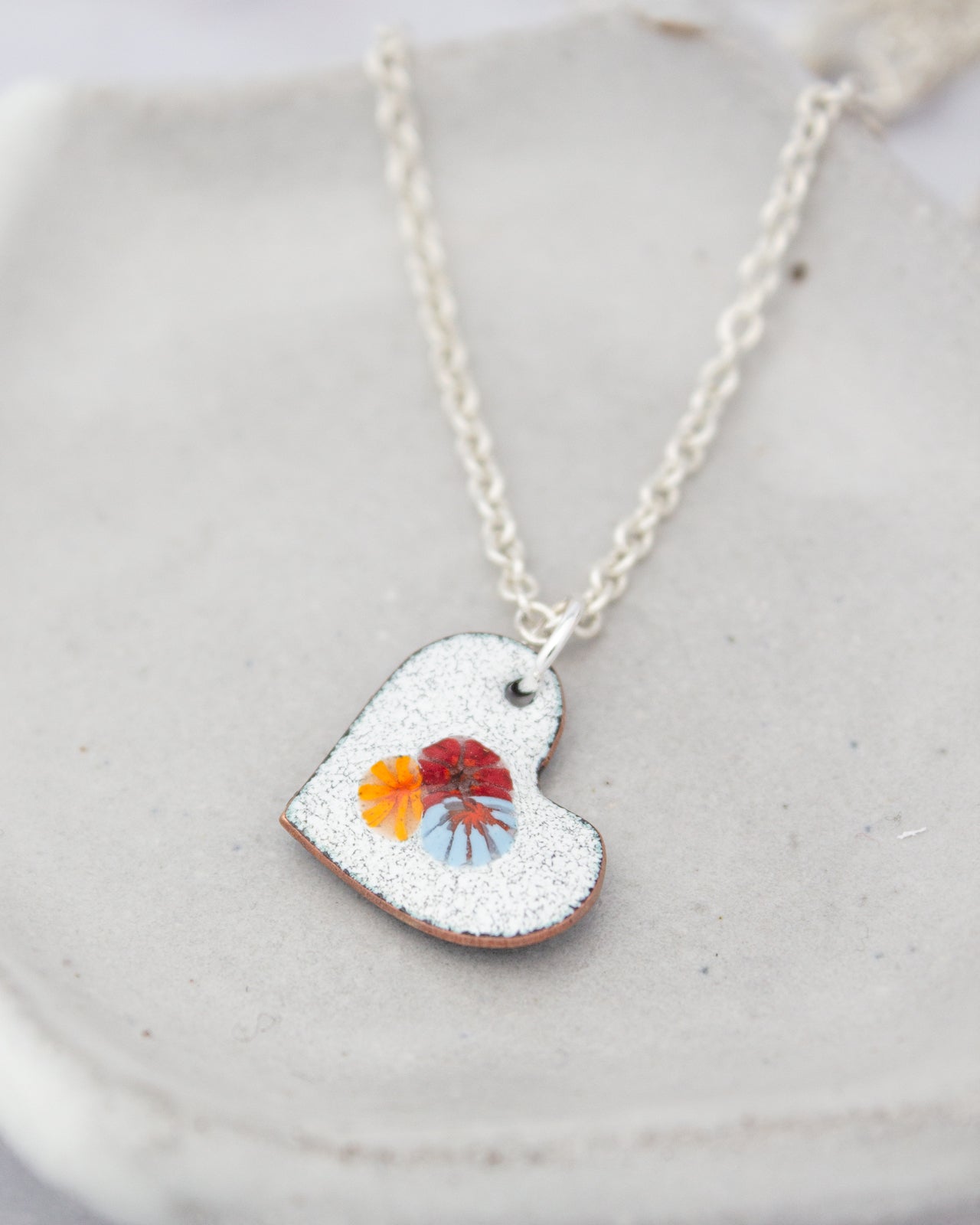 A heart-shaped pendant with a colorful design is displayed on a white surface.