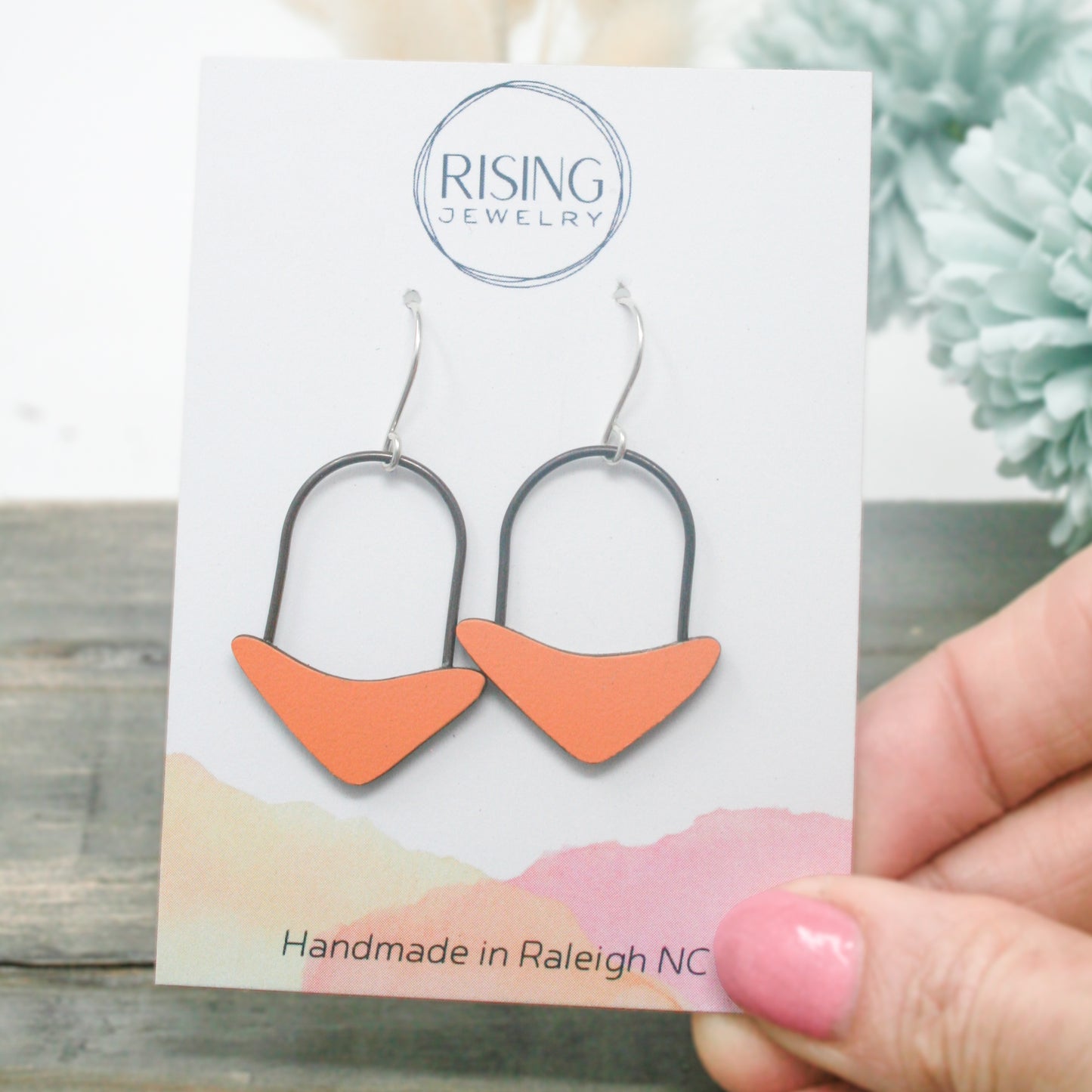 a pair of orange and black earrings on a card