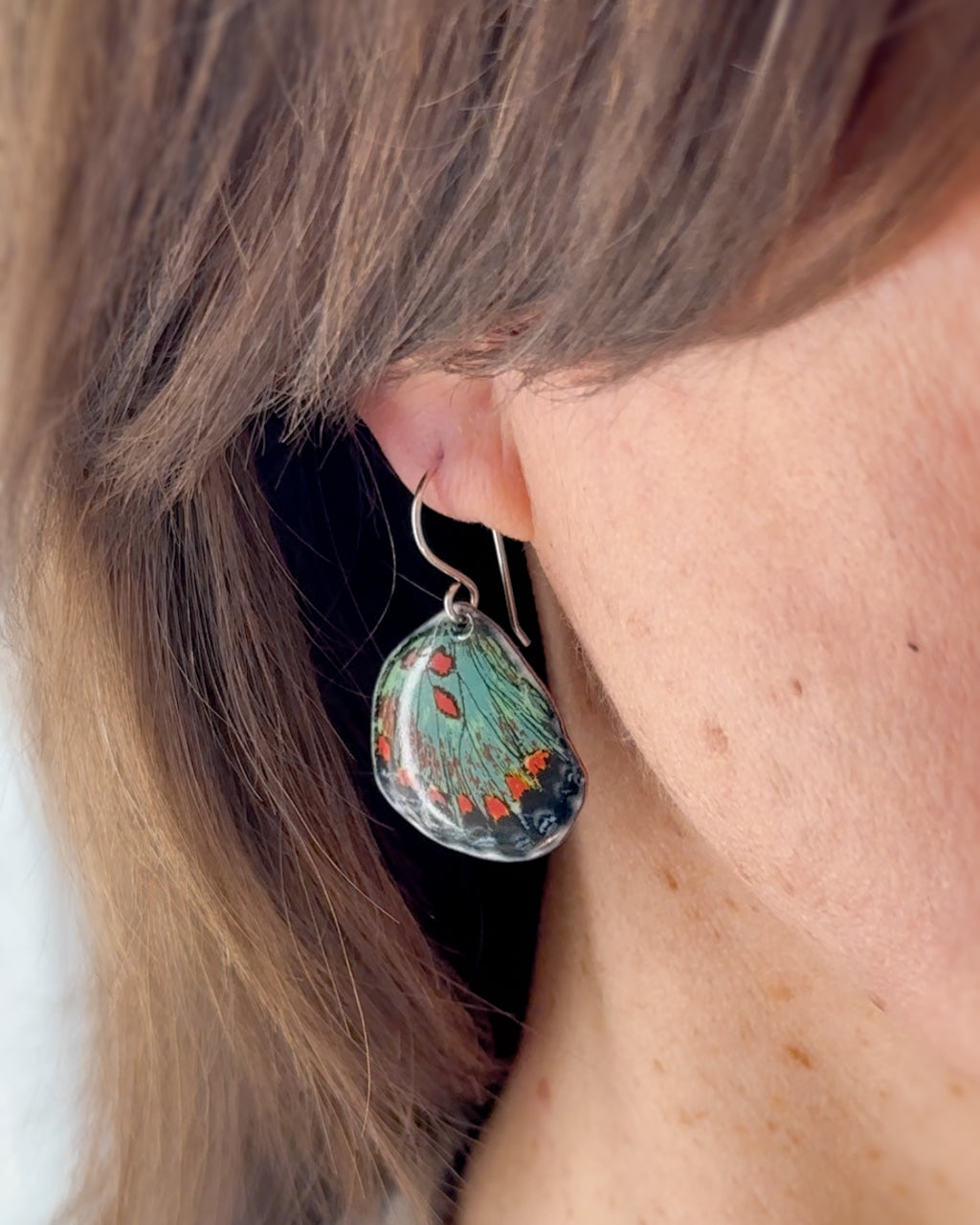 a close up of a person wearing a pair of earrings