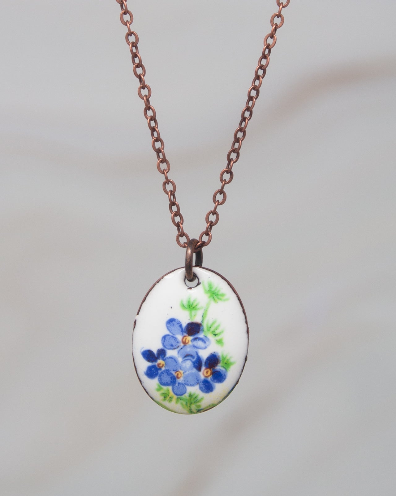A necklace with a pendant featuring a blue flower design.