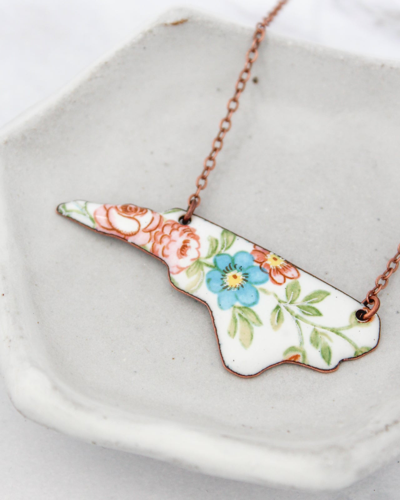 A necklace with a floral design on a white ceramic plate.