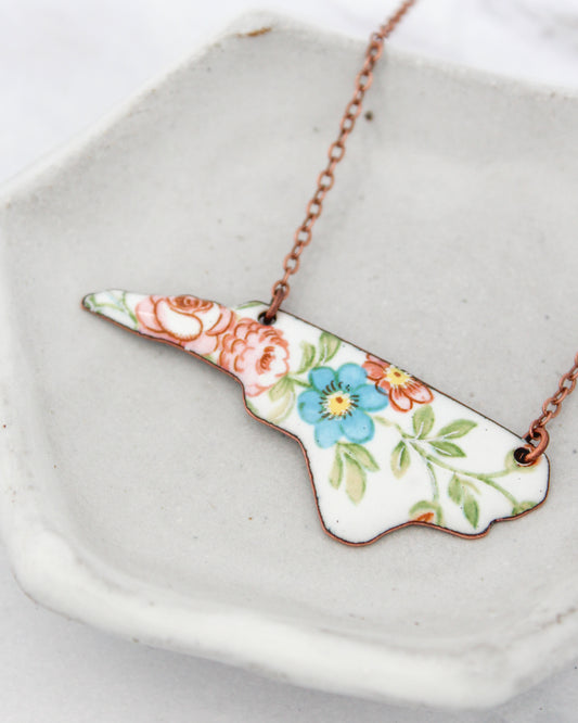A necklace with a floral design on a white ceramic plate.