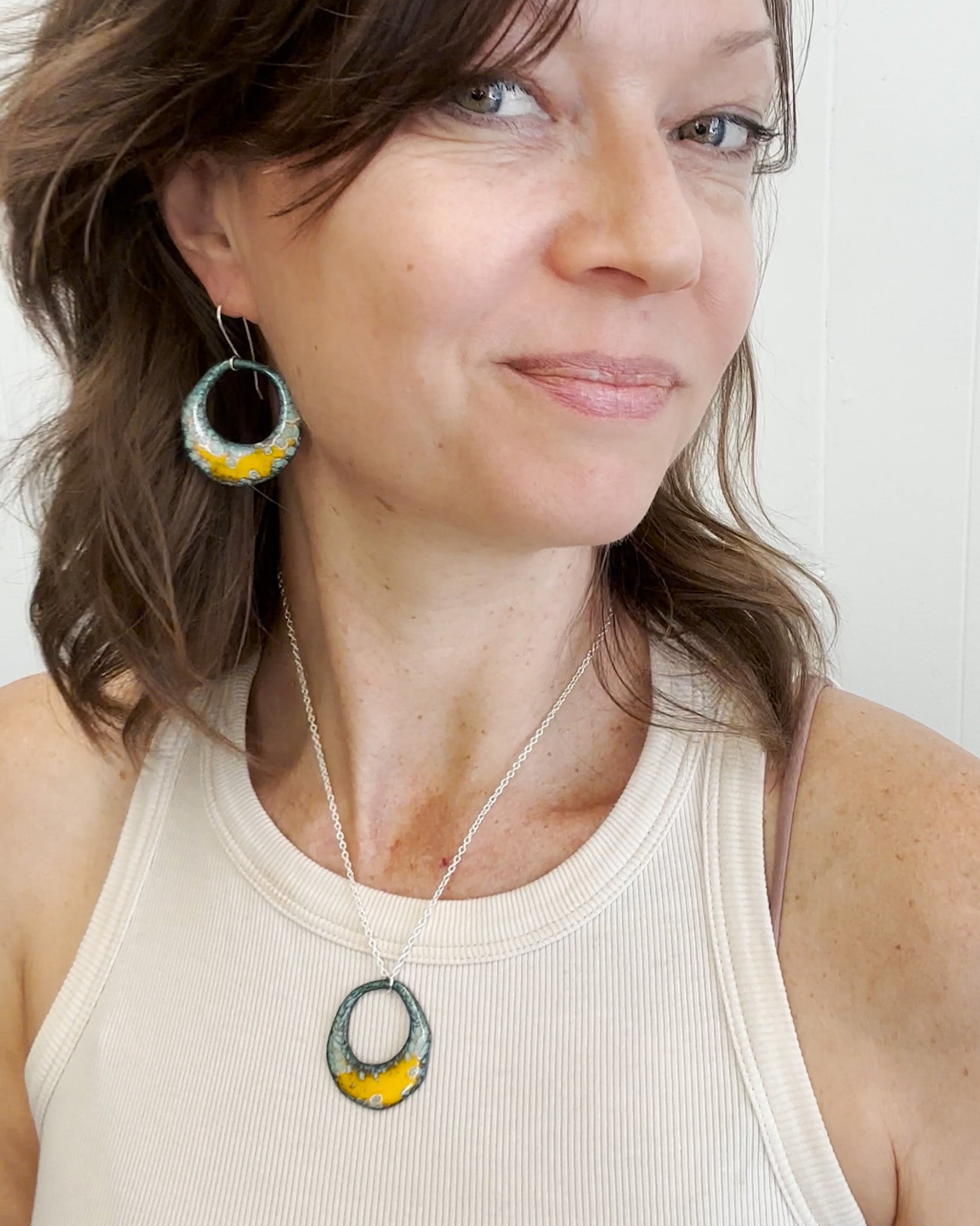 a woman in a tank top wearing a pair of earrings