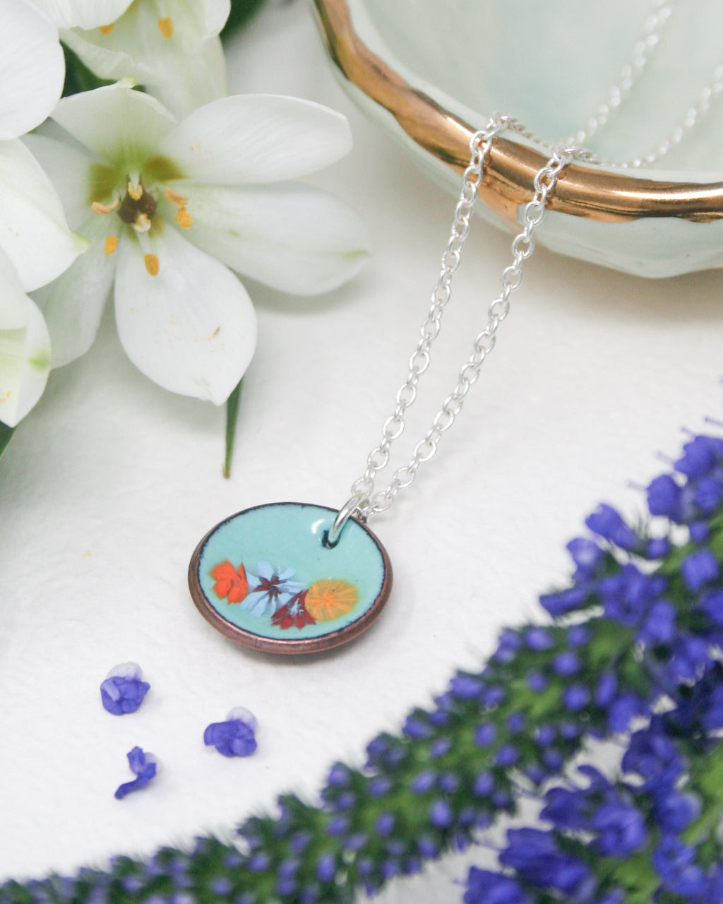 a close up of a necklace with flowers in the background