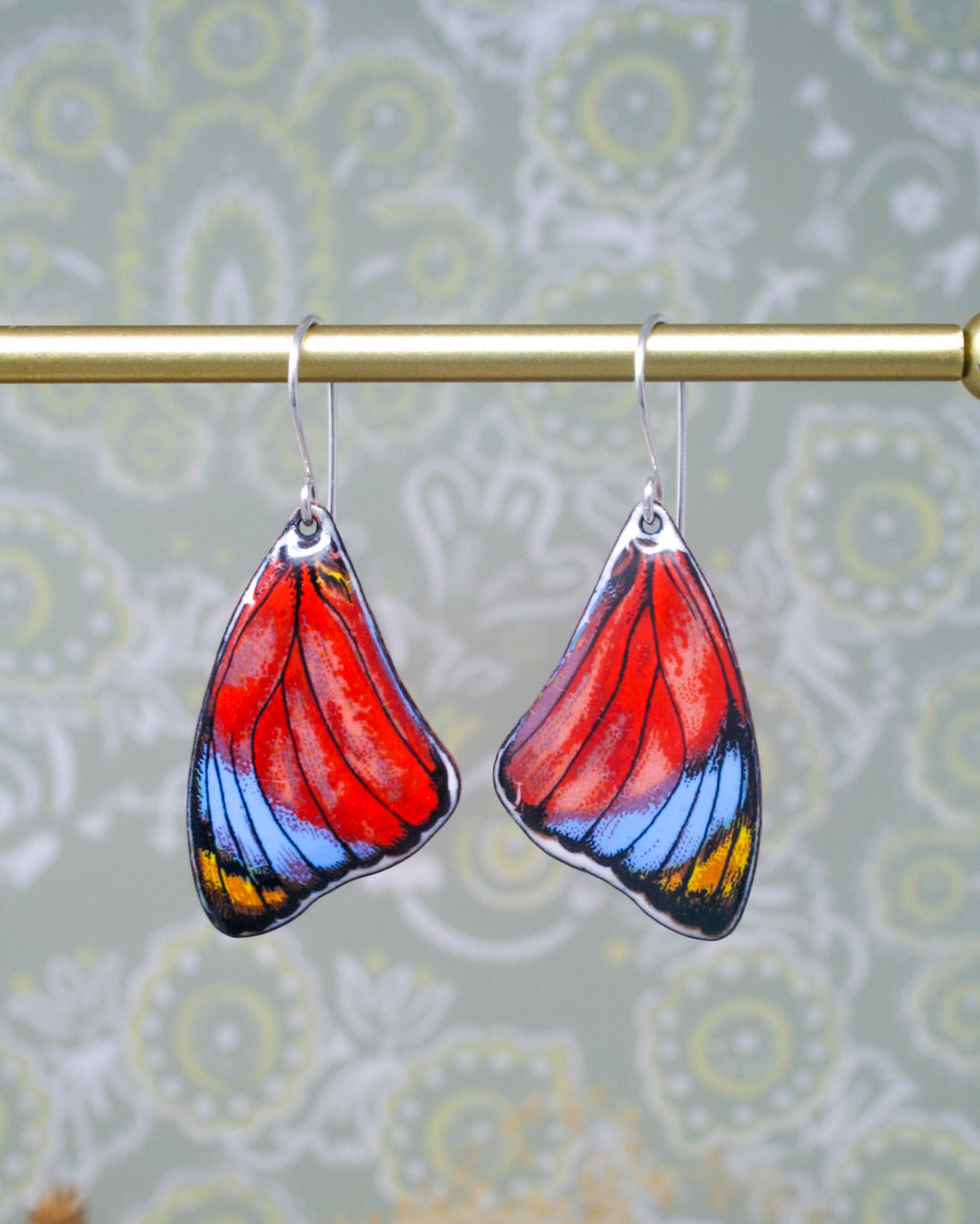 a pair of colorful glass earrings hanging from a metal rod