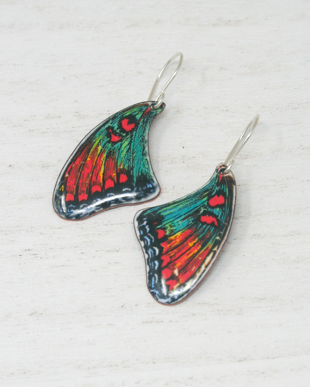 a pair of butterfly shaped earrings on a white surface