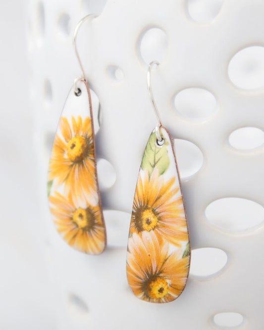 A pair of earrings with a floral design, featuring yellow flowers on a white background.