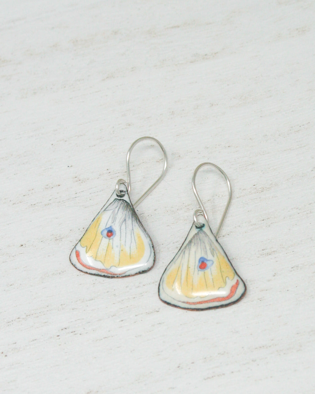 a pair of yellow and white earrings on a white surface