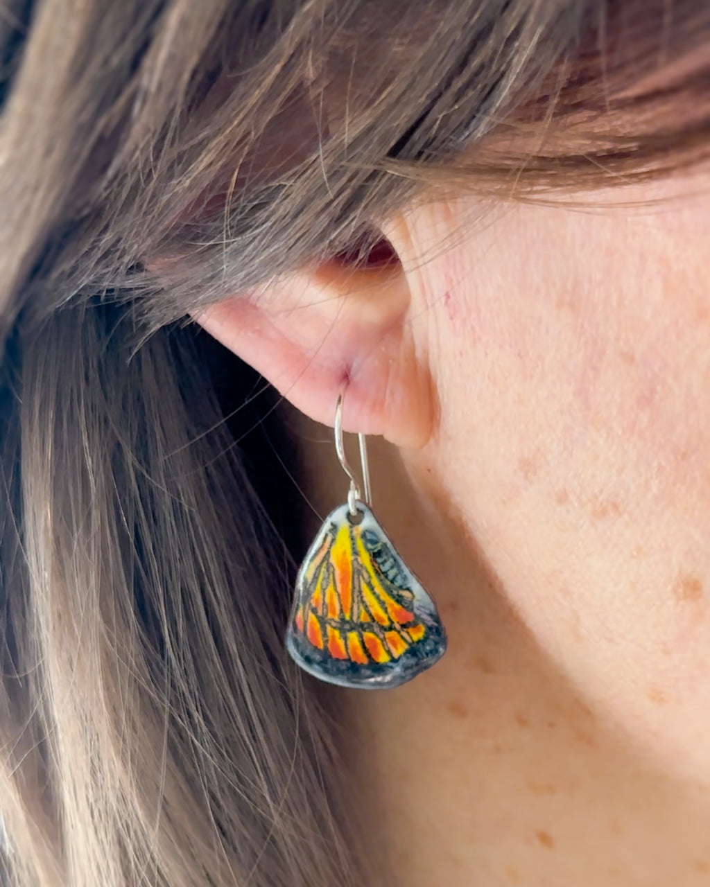 a close up of a person wearing a pair of earrings