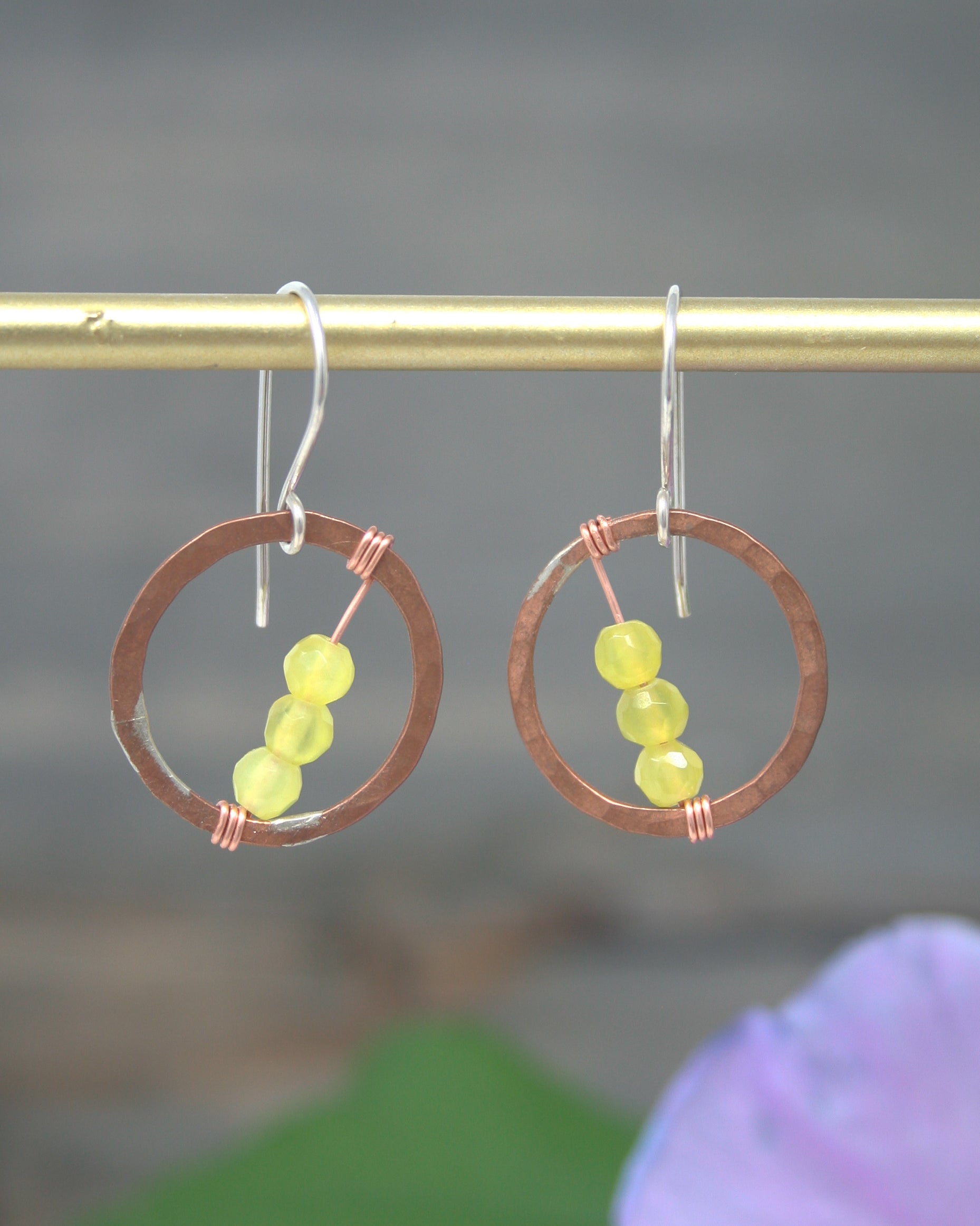 a pair of earrings hanging from a metal rod