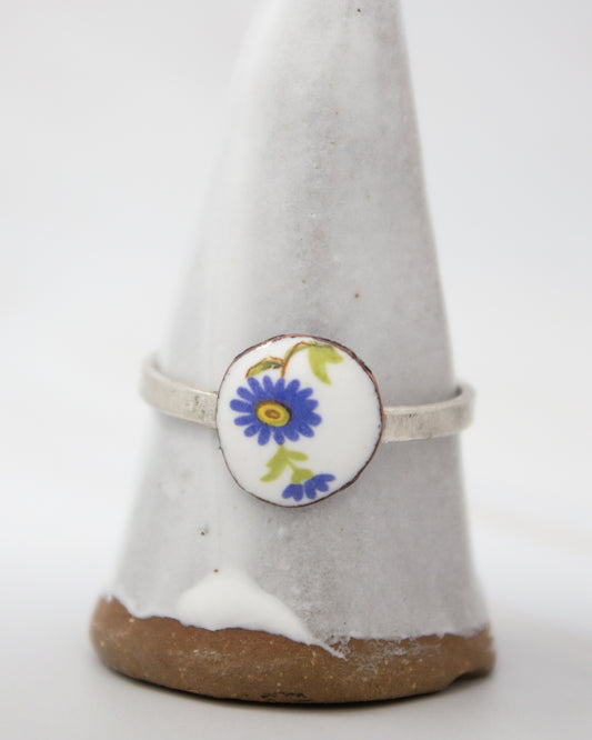 A white ceramic ring stand with a blue and yellow floral design on it.