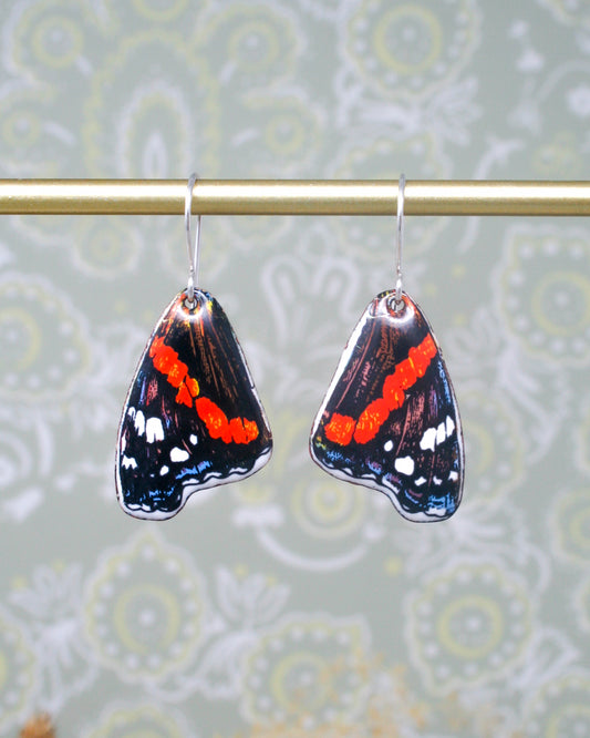 a pair of butterfly shaped earrings hanging from a clothes line