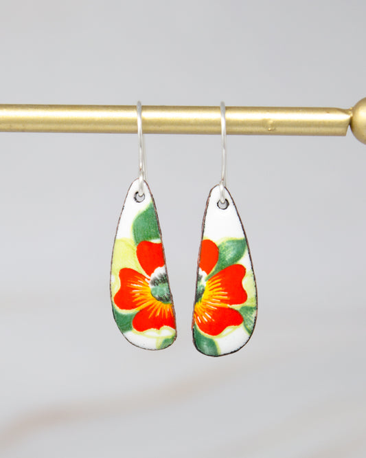 A pair of earrings with a floral design, featuring red and green flowers on a white background.