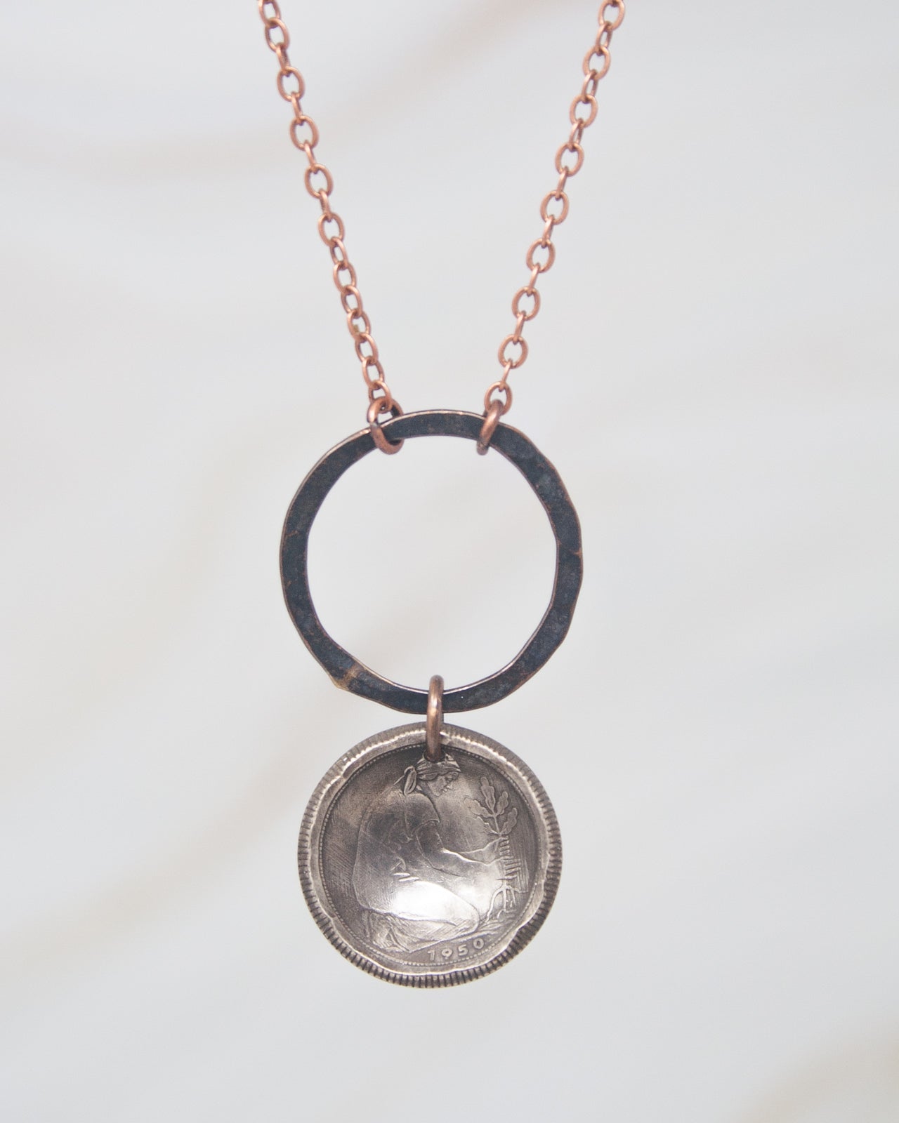 A necklace with a circular pendant featuring a coin design and a chain.