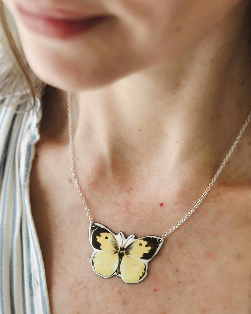 a woman wearing a yellow and black butterfly necklace