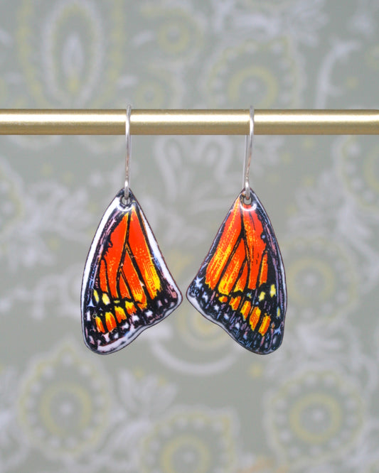 a pair of orange and black butterfly earrings