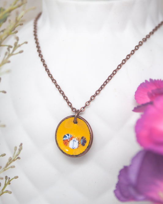 A necklace with a circular pendant featuring a vibrant yellow and blue design, surrounded by a chain and placed on a white mannequin head.