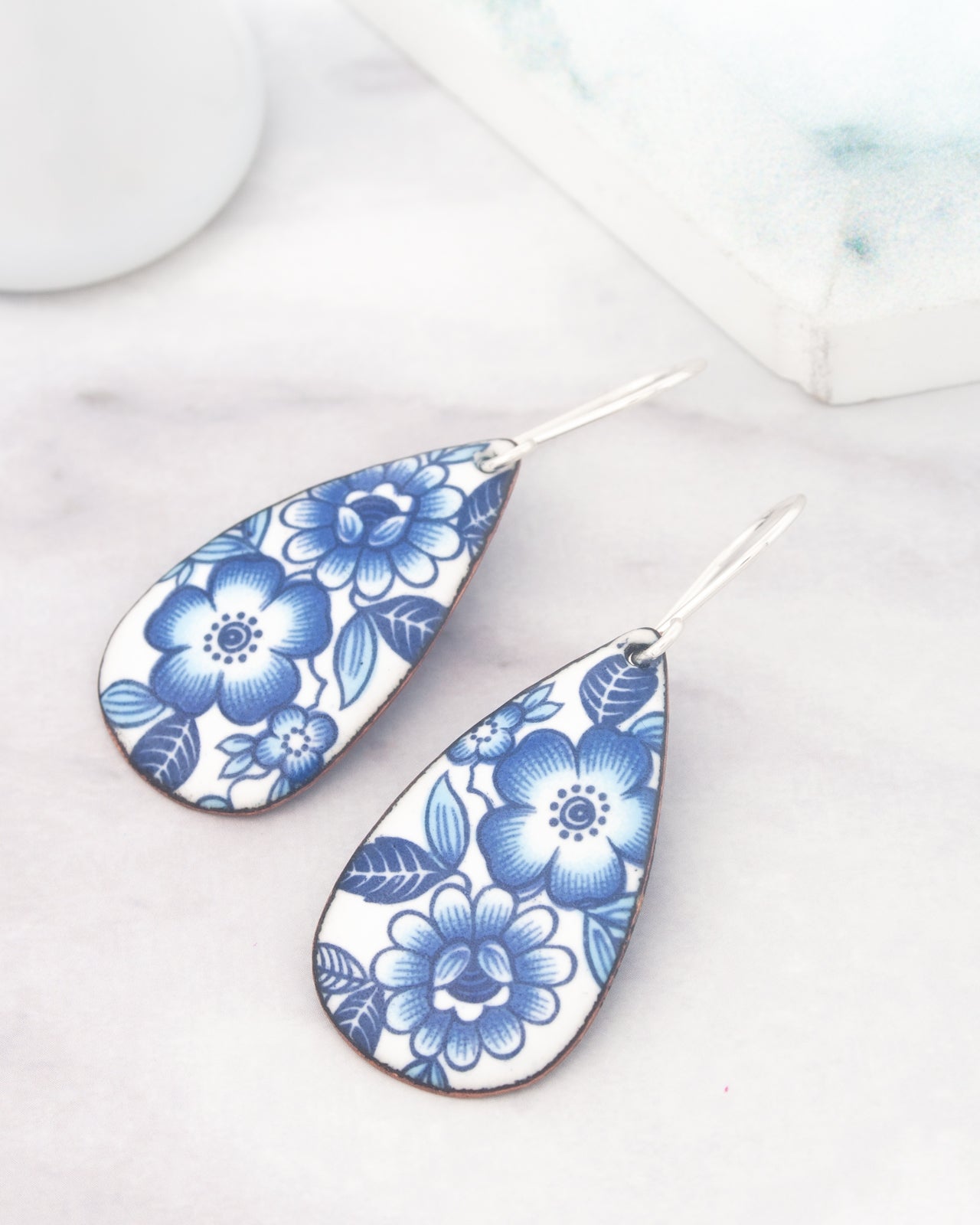 a pair of earrings with a blue floral design on a white background.