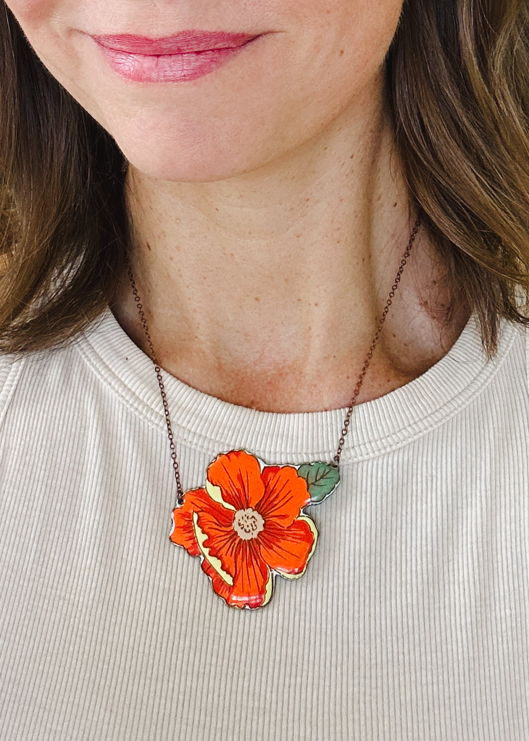 a woman wearing a necklace with a flower on it