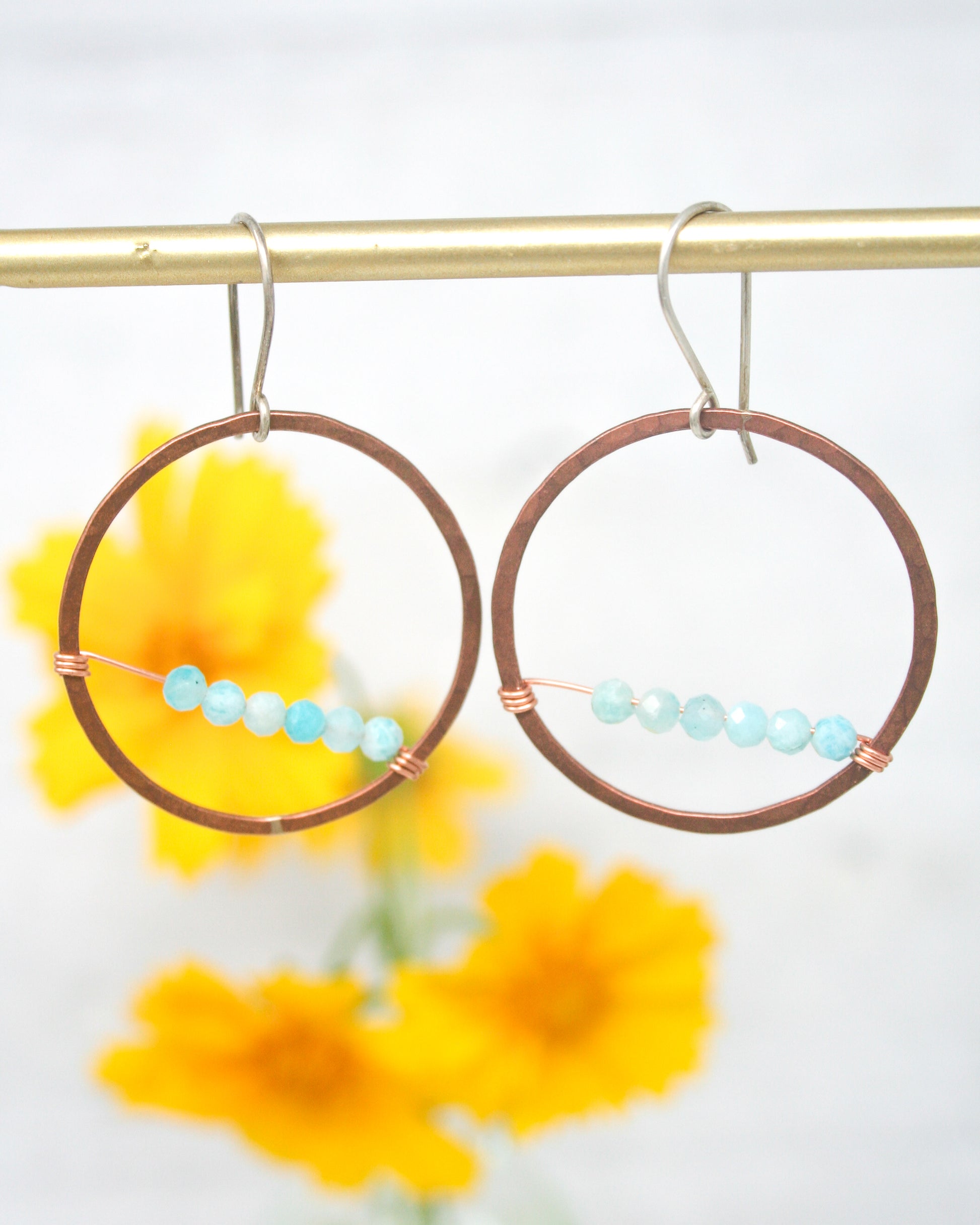 a pair of hoop earrings with beads hanging from them