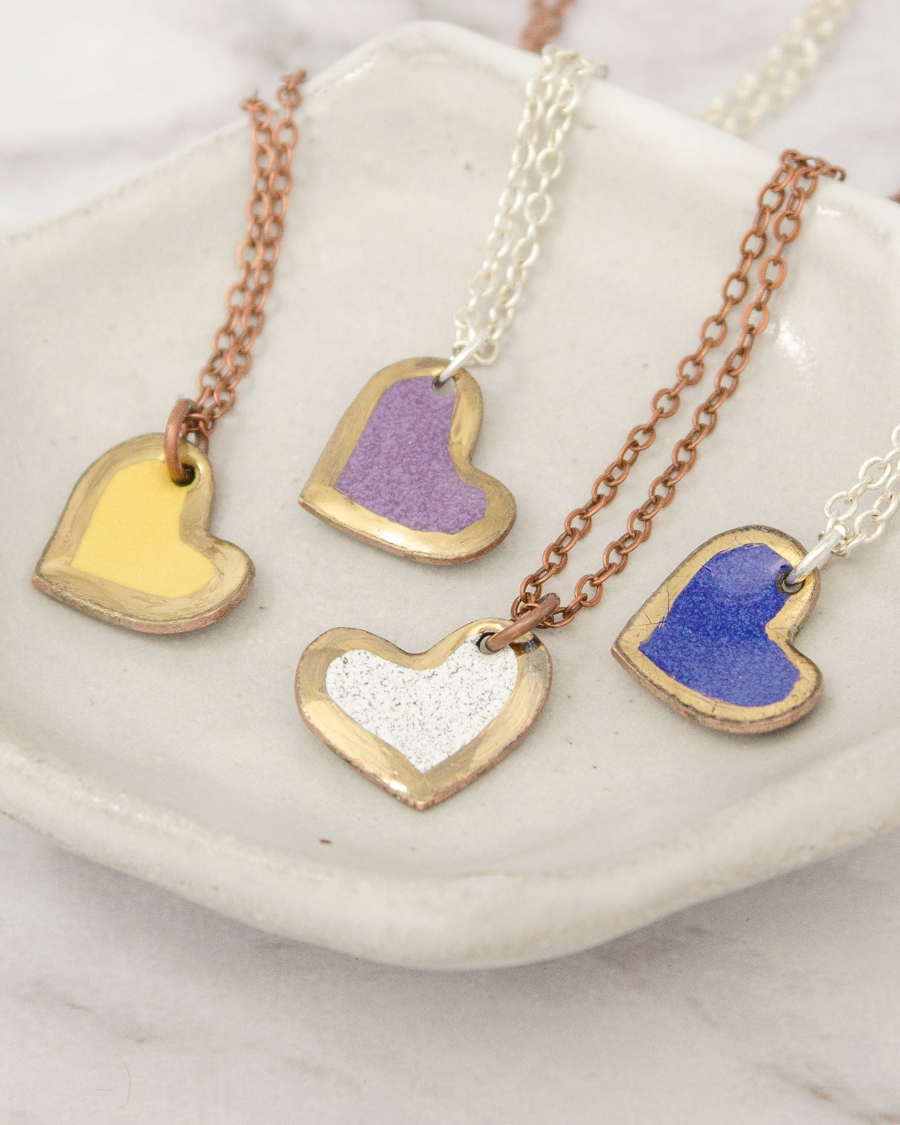 a collection of heart-shaped pendants with different colors and designs, arranged on a white plate or tray.