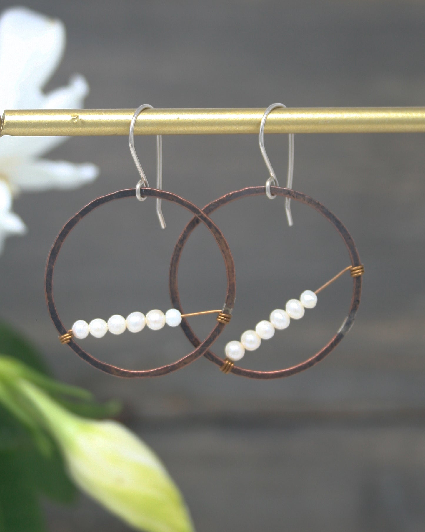 a pair of earrings with pearls hanging from a hook