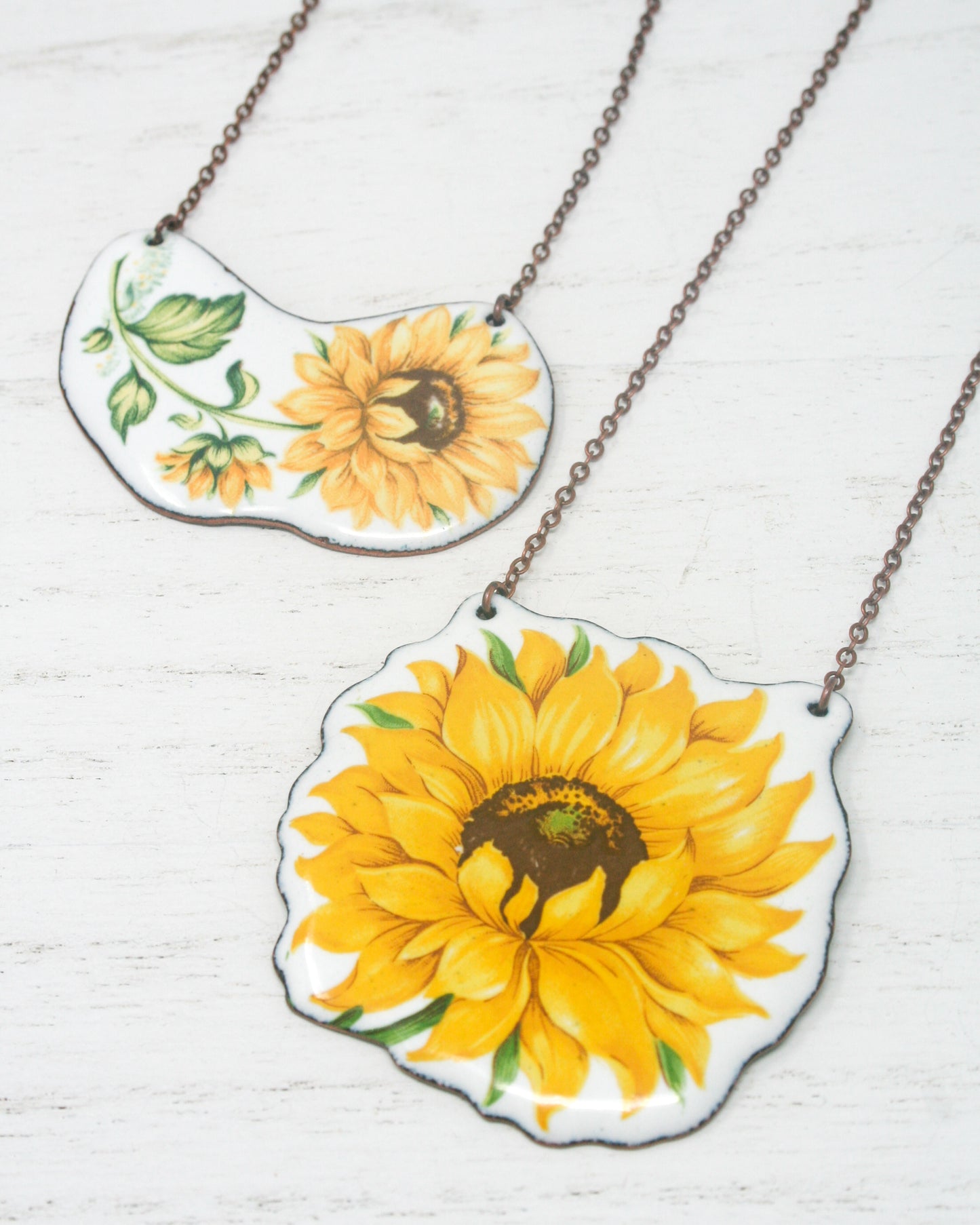 two yellow sunflowers painted on a white plate on a chain