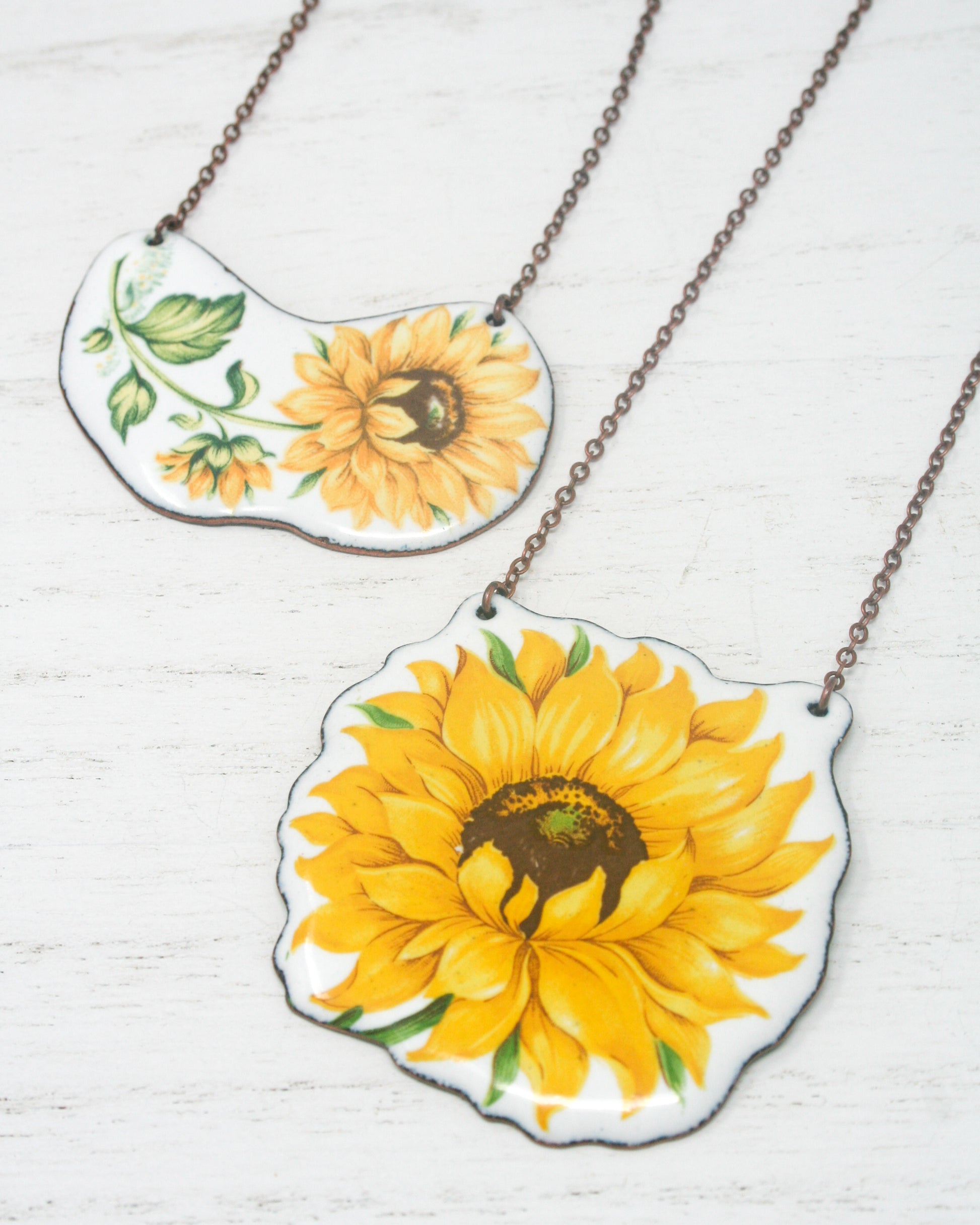 two yellow sunflowers painted on a white plate on a chain