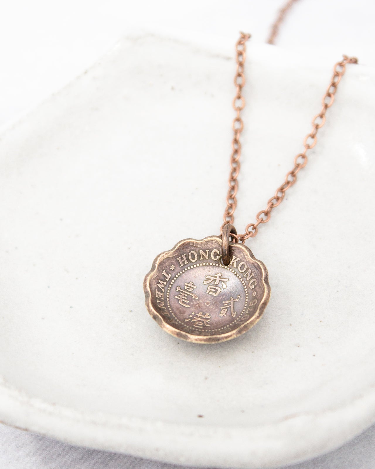 A necklace with a pendant featuring a Hong Kong coin.