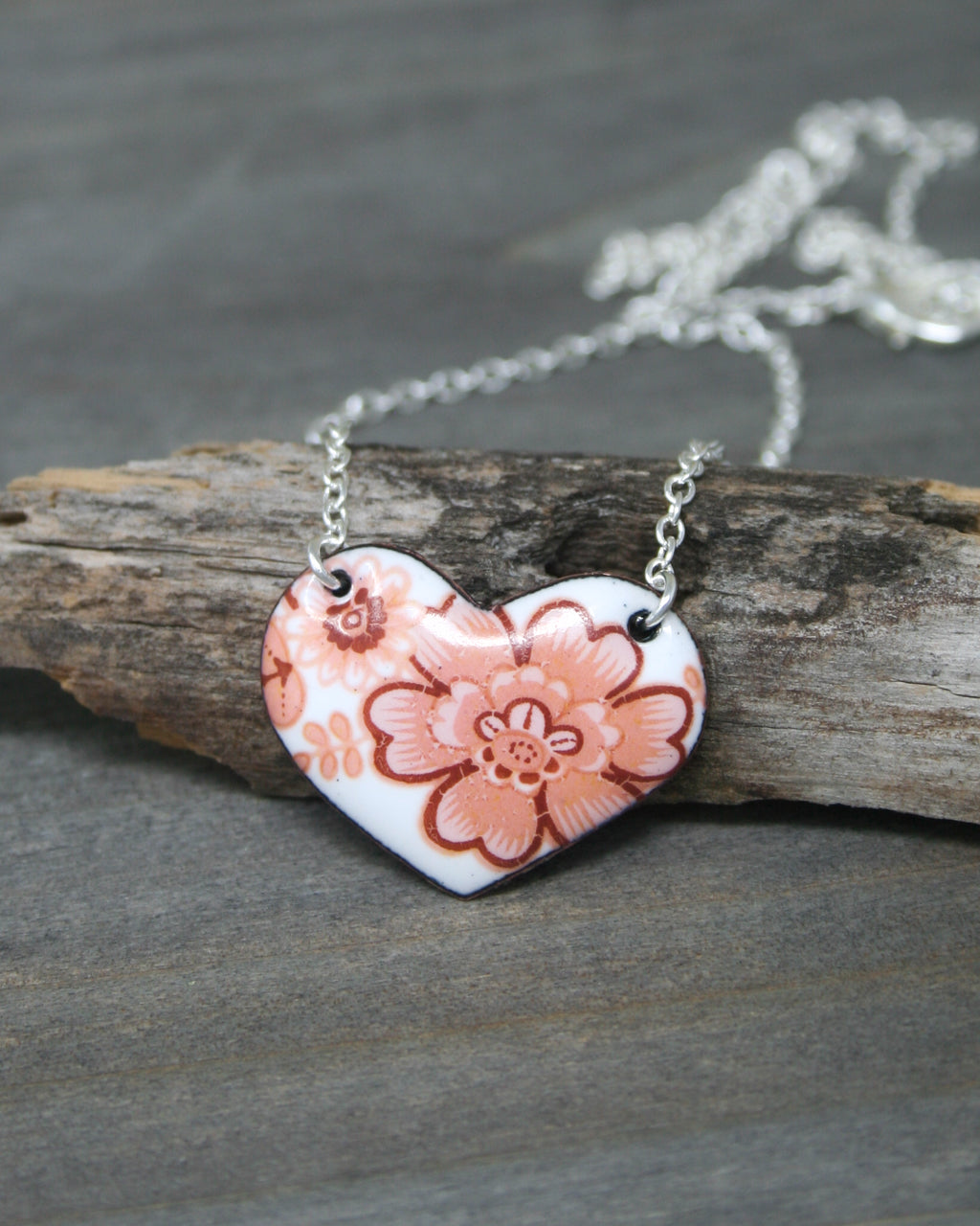 a heart shaped necklace with a flower on it