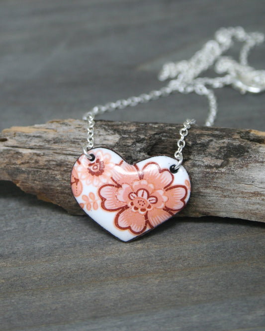 a heart shaped necklace with a flower on it