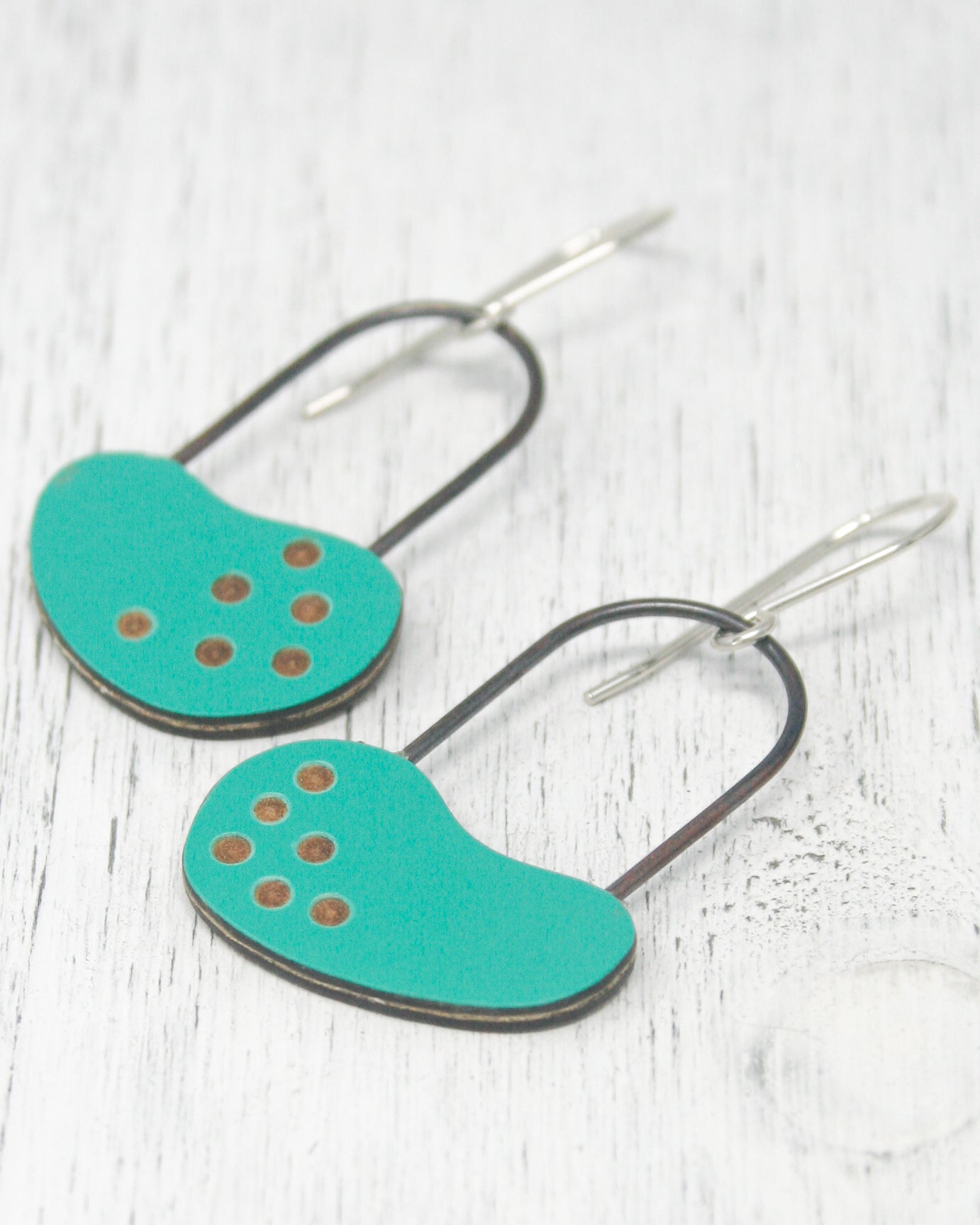 A pair of turquoise earrings with black metal accents and small circular dots on the surface.