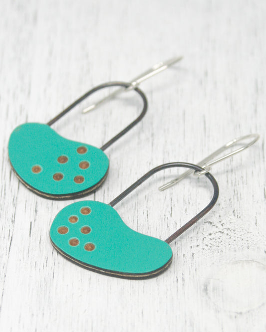 A pair of turquoise earrings with black metal accents and small circular dots on the surface.