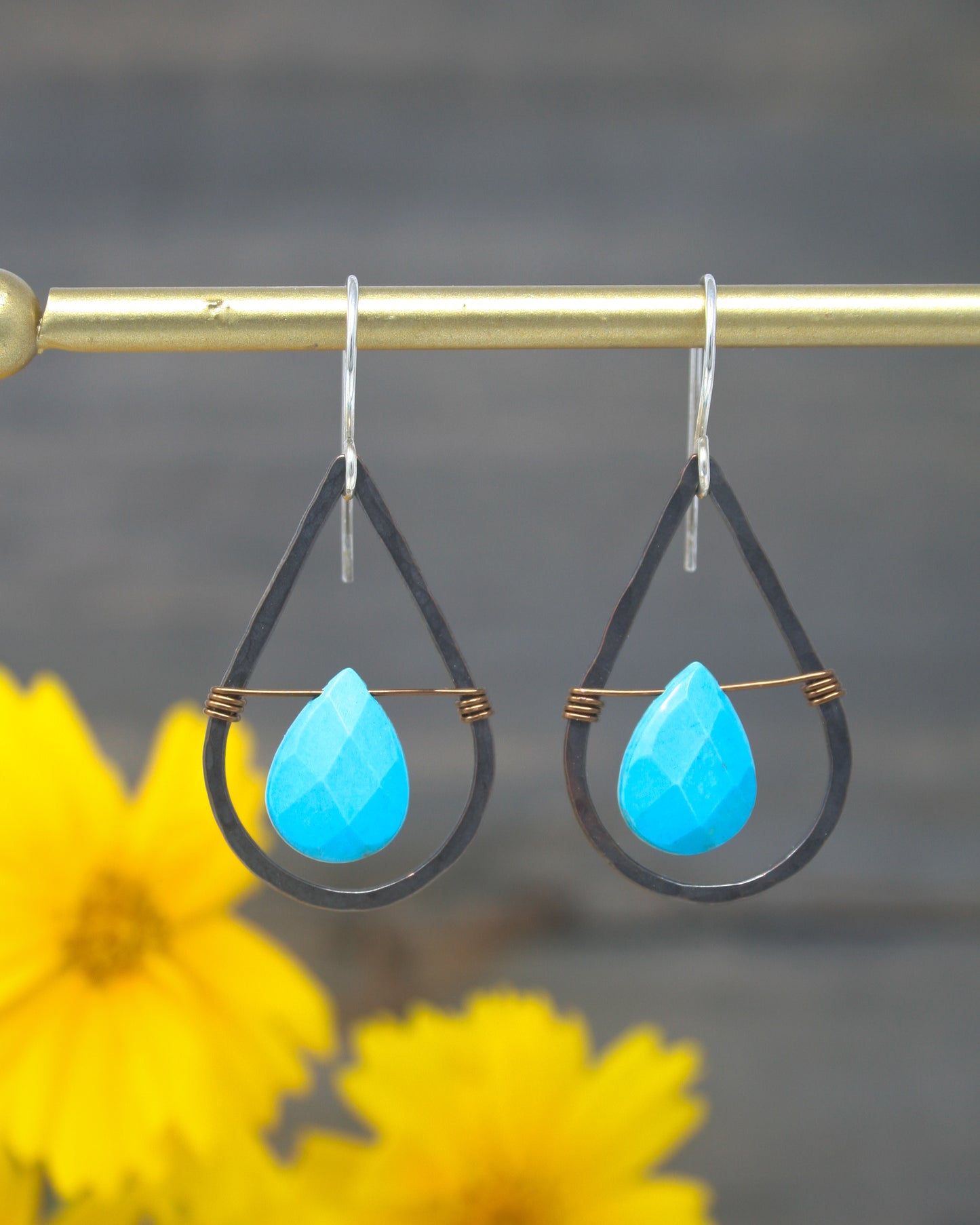 a pair of earrings hanging from a metal bar