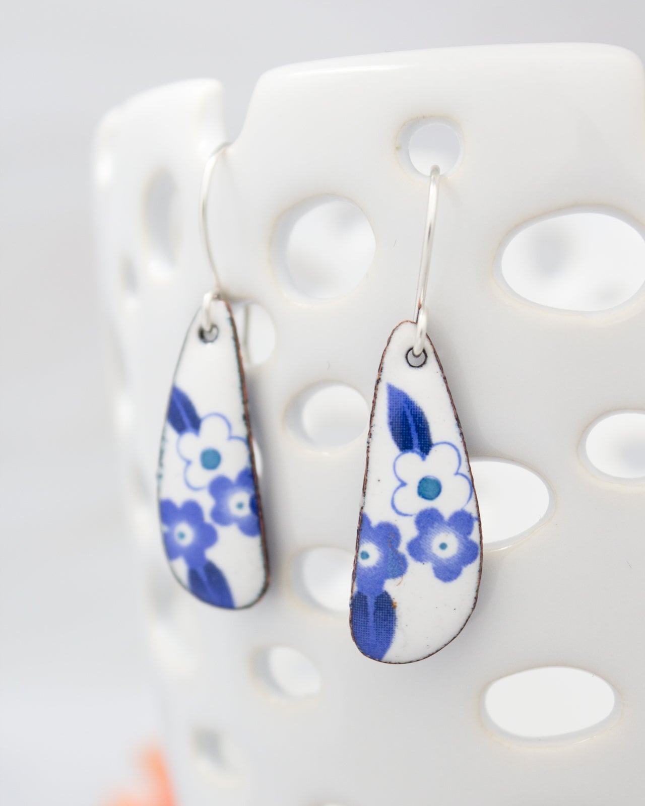 A pair of earrings with blue floral designs on a white background.